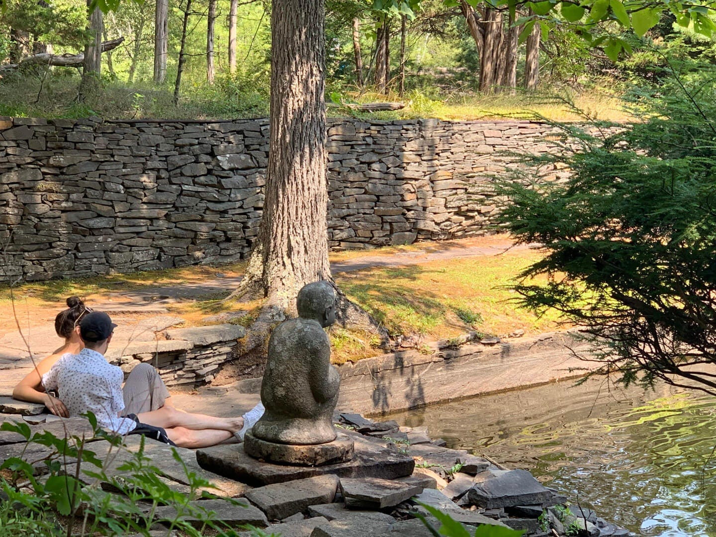 A couple sitting by a pond at Opus 40