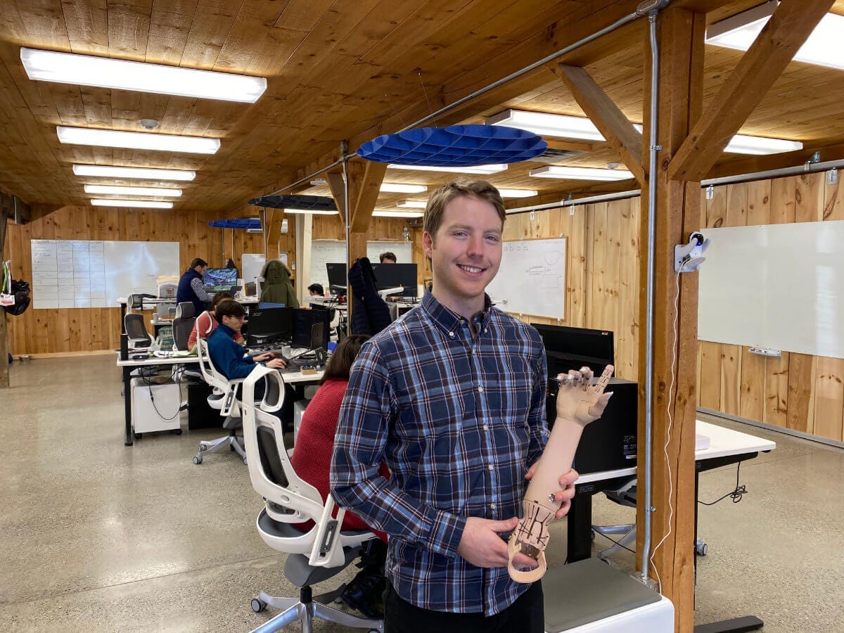 Easton LaChappelle holding a prosthetic arm at Unlimited Tomorrow headquarters in Rhinebeck